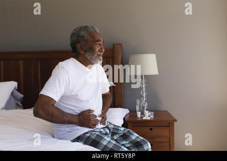 Senior l uomo che soffre di mal di stomaco in camera da letto Foto Stock