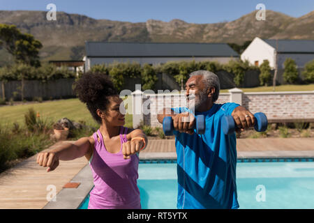 Trainer femmina assistere senior uomo in esecuzione di esercizio Foto Stock