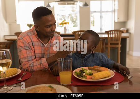 Padre tergi figli bocca con igienico dopo pasto sul tavolo da pranzo Foto Stock