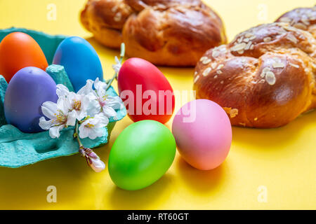 Uova di Pasqua e tsoureki treccia, la Pasqua greca pane dolce, su giallo colore di sfondo Foto Stock