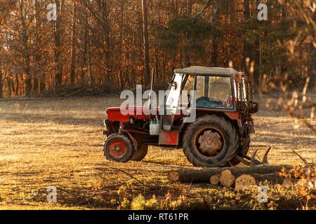 Il vecchio trattore rosso sul bordo di una foresta. Lavoro in foresta. Un trattore abbandonati. Il paesaggio della campagna ceca. Foto Stock