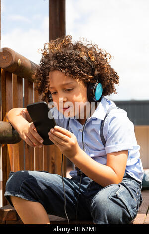Schoolgirl utilizzando il telefono cellulare nella scuola parco giochi Foto Stock
