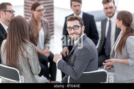 Giovane lavoratore seduto in un cerchio di colleghi Foto Stock