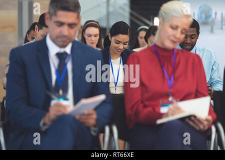 Giovane imprenditrice iscritto sul blocco note in un seminario di business Foto Stock