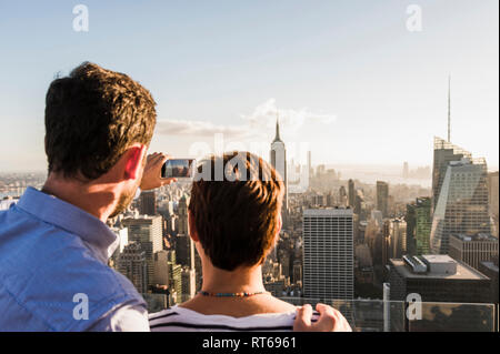 Stati Uniti d'America, New York City, l'uomo con la donna prendendo cellulare immagine sul Rockefeller Center observation deck Foto Stock