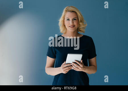 Ritratto di sorridere donna bionda azienda tablet Foto Stock