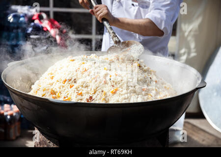 Pentola grande con il plov nazionale cibo Kazako sulla strada di Almaty Nauryz durante il festival in Kazakistan Foto Stock