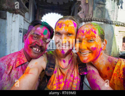 Udaipur, India - 6 Marzo 2015: Foto Selfie indiana di uomo e coppia estera con faccia dipinta celebrando il coloratissimo festival di Holi sulla stree Foto Stock