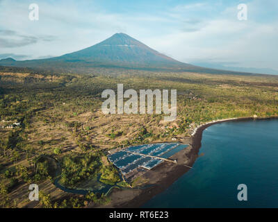 Indonesia, Bali, Amed, vista aerea di allevamento di gamberetti e di vulcano Agung in background Foto Stock