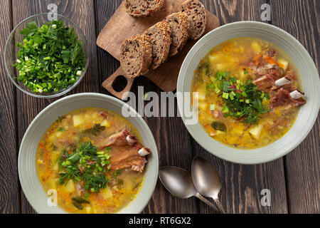 Giallo dividere la zuppa di piselli con carne di maiale affumicato nervature servita in piastre su un tavolo di legno. Vista superiore Foto Stock