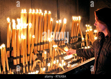 Donna alleggerimento di una candela a devozione altare Foto Stock