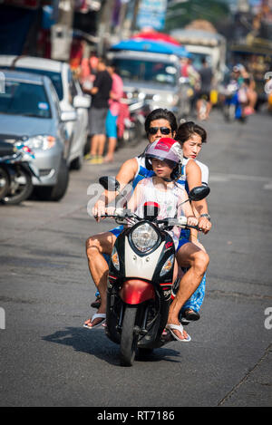 Famiglia in sella ad un ciclomotore lungo una strada a Phuket, Tailandia. Foto Stock