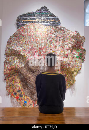 Ottobre Gallery di Londra, Regno Unito. Il 28 febbraio, 2019. El Anatsui: materiale caratteristiche di meraviglia di scultori del Ghana distintiva grande e intricato parete metallica le sculture realizzate da assemblaggi di alluminio di tappi di bottiglie di alcol da stazioni di riciclaggio cucite insieme con il filo di rame. Immagine: galleria personale con Iris, 2012. Credito: Malcolm Park/Alamy Live News. Foto Stock