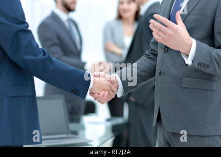 Business Partner per lo handshaking oltre gli oggetti business sul posto di lavoro Foto Stock