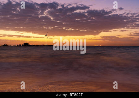 Fonti di energia con le turbine eoliche in mare nel tramonto Foto Stock