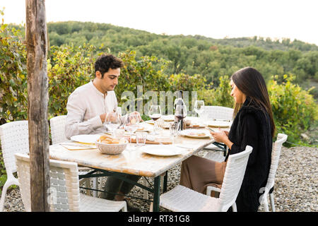 L'Italia, Toscana, Siena, coppia giovane a cena in un vigneto Foto Stock