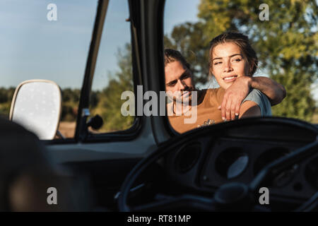 Affettuosa giovane in piedi con il loro camper con bracci intorno Foto Stock