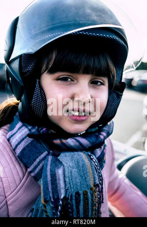Ritratto di bambina con dente divario che indossa il casco su motociclo Foto Stock