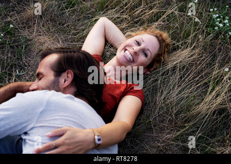 Coppia felice cuddling, sdraiato su un prato Foto Stock