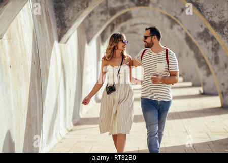 Spagna, Andalusia, Malaga, felice turista giovane camminare sotto un arco in città Foto Stock