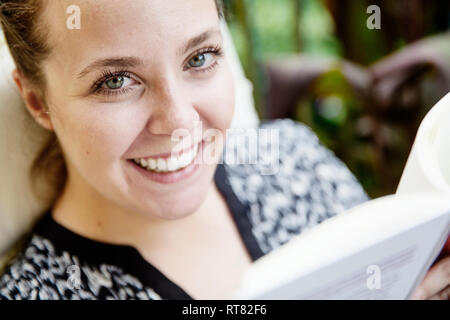 Ritratto di felice giovane donna leggendo un libro sul balcone Foto Stock