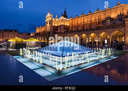 La Polonia, Cracovia, piazza principale nella Città Vecchia di notte, fontane illuminate di panno e Hall Foto Stock