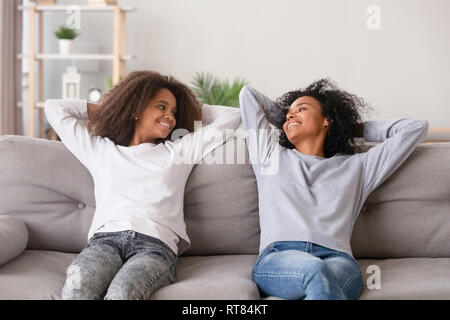 Positivo nero madre e figlia in appoggio sul lettino a casa Foto Stock