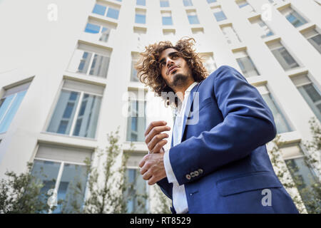 Ritratto di giovane imprenditore con barba e capelli ricci indossare tuta blu Foto Stock