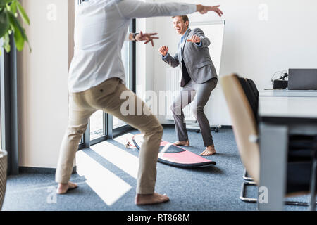 Due colleghi giocoso con la tavola da surf in office Foto Stock