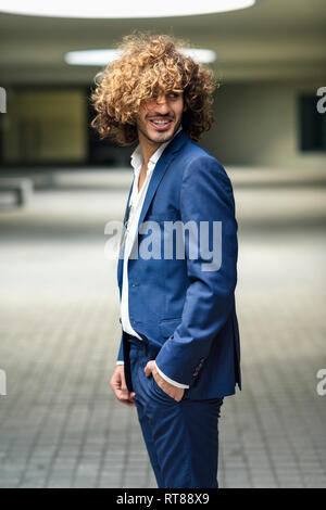 Ritratto di giovane imprenditore alla moda con capelli ricci indossare tuta blu Foto Stock