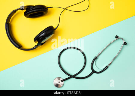 Concetto di scelta proffesion. È meglio essere un dj o un medico. Cuffie e uno stetoscopio su sfondo colorato. Foto Stock