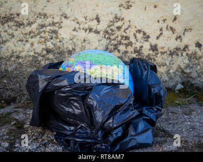 Un globo terrestre o pianeta terra tra la spazzatura e sacchetti di plastica. Concetto di ecologia Foto Stock