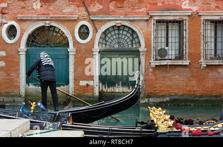 Venezia, Italia - 12 Gennaio 2019: un gondoliere sul suo gondola davanti alla facciata di un edificio storico Foto Stock