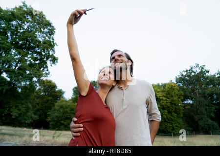 Coppia felice tenendo selfies all'aperto Foto Stock