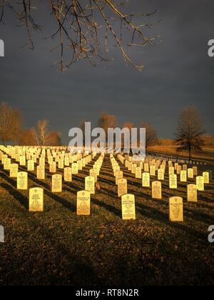 La rastrellatura luce rende lapidi glow come oro Lingotti a Camp Nelson Cimitero Nazionale vicino Nicholasville Ky., Gen 28, 2019. Durante la guerra civile, il Camp Nelson è stata la casa di un 700-letto Union Army hospital, numerosi negozi per il lavoro del fabbro e la costruzione dei carri e ambulanze, artiglieria, di storage e di una stazione di arruolamento per afro-americano di soldati. Il cimitero attualmente è la casa di migliaia di militari statunitensi internments risalente al 1860 al giorno moderno, compresi i veterani del Kentucky Air National Guard. Foto Stock