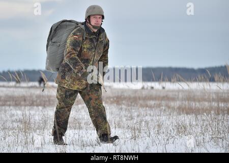 Un paracadutista tedesco passeggiate fuori dalla zona di caduta durante un 4° Battaglione, campo 319reggimento di artiglieria, 173rd Airborne vigili del salto di formazione con la multinazionale partner provenienti da Regno Unito, in Germania e in Spagna con il settimo Esercito di formazione del comando di Grafenwoehr Area Formazione, Germania, 29 gennaio, 2019. Foto Stock