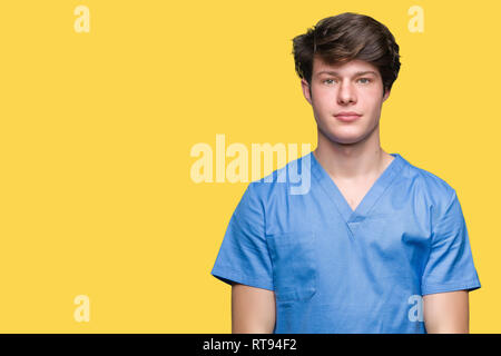 Giovane medico medico che indossano uniformi su sfondo isolato con espressione seria sul viso. Semplice e naturale guardando la telecamera. Foto Stock