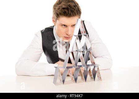 Focalizzato l'uomo facendo piramide da carte da gioco isolato su bianco Foto Stock