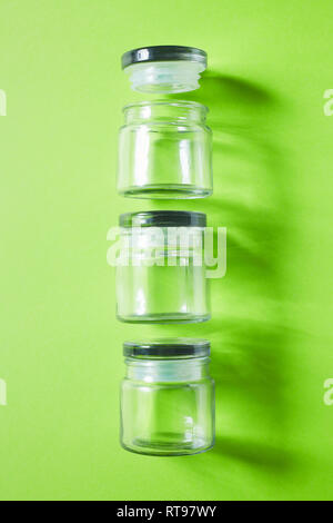 Bicchiere vuoto nella conservazione di alimenti vasi su sfondo verde, laici piatta Foto Stock