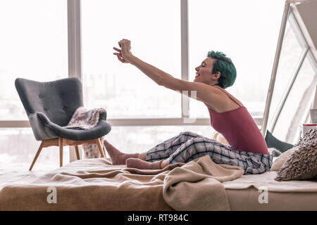 Donna felice stretching il suo corpo mentre svegliarsi al mattino Foto Stock