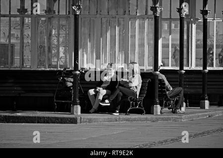 Immagine monocromatica di 2 donna seduta su una panchina in un rifugio in stile vittoriano a New Brighton MERSEYSIDE REGNO UNITO. Foto Stock