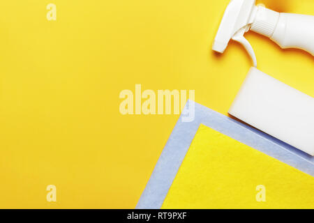La bottiglia spray di detersivo e spugna e tovagliolo su sfondo giallo. Il concetto di pulizia Foto Stock