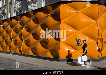Una shopper passa per il temporaneo di accaparramento di rinnovamento del marchio di lusso di Louis Vuitton a New Bond Street, il 25 febbraio 2019, a Londra, in Inghilterra. Foto Stock