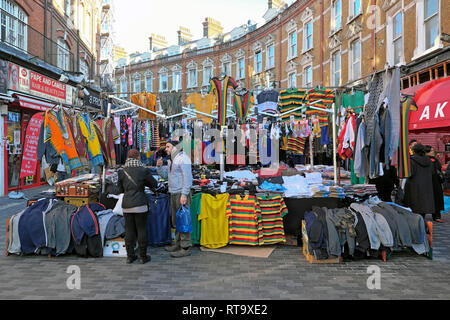 Un mercato trader uomo vendita di abbigliamento e magliette da calcio in Brixton street market Electric Avenue Brixton a sud di Londra Inghilterra REGNO UNITO KATHY DEWITT Foto Stock