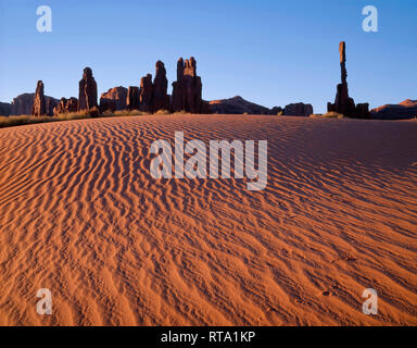 Stati Uniti d'America, Arizona, il parco tribale Navajo, Sunrise definisce la texture di dune di sabbia con torri di roccia chiamato Yei-Bi-Chei aumento nella distanza; Monument Valley. Foto Stock