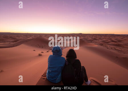 La gente sta guardando la sorprendente alba sulle dune Erg Chebbi nel deserto del Sahara . Bella sabbia paesaggio con incredibile cielo. Merzouga, Marocco Foto Stock