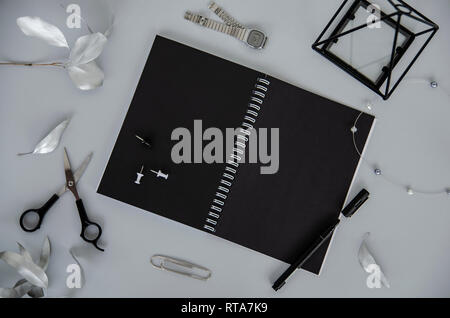 Decorate piatto design laici. Notebook su spirale con fogli nero su sfondo grigio. Foto Stock