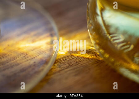 Solare pattern attraverso una bottiglia di vetro olio riflessa su una base di legno Foto Stock