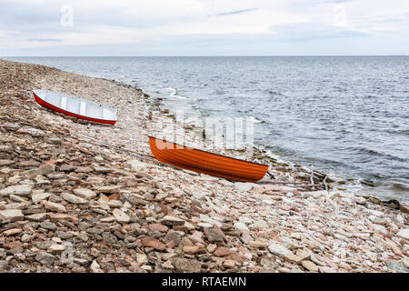 Barche a remi tirata su di una spiaggia rocciosa e dal mare Foto Stock