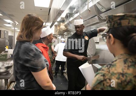 Lancia Cpl. Salim Bayo mostra Morongo Unified School District agli studenti come il pollo alla griglia a Phelps Hall dining facility, Marine Corps Air Ground Centro di combattimento, ventinove Palms, California, durante il combattimento Scuola centrale di collegamento 16 del lavoro annuale evento di shadowing, 6 febbraio 2019. Foto Stock